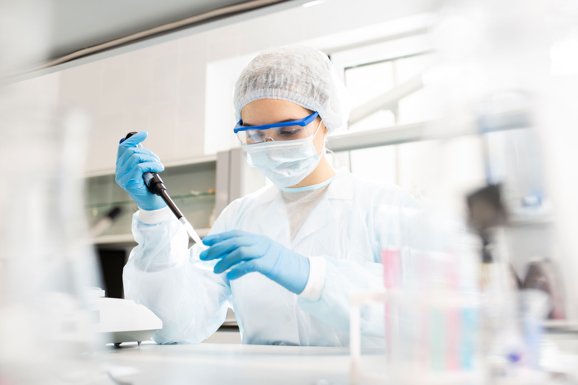 woman in lab using syringe on petri dish