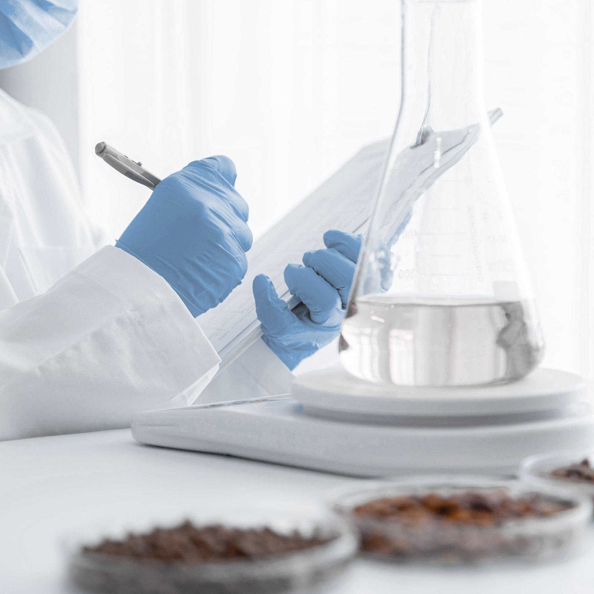 person's hands in lab with gloves writing on clipboard