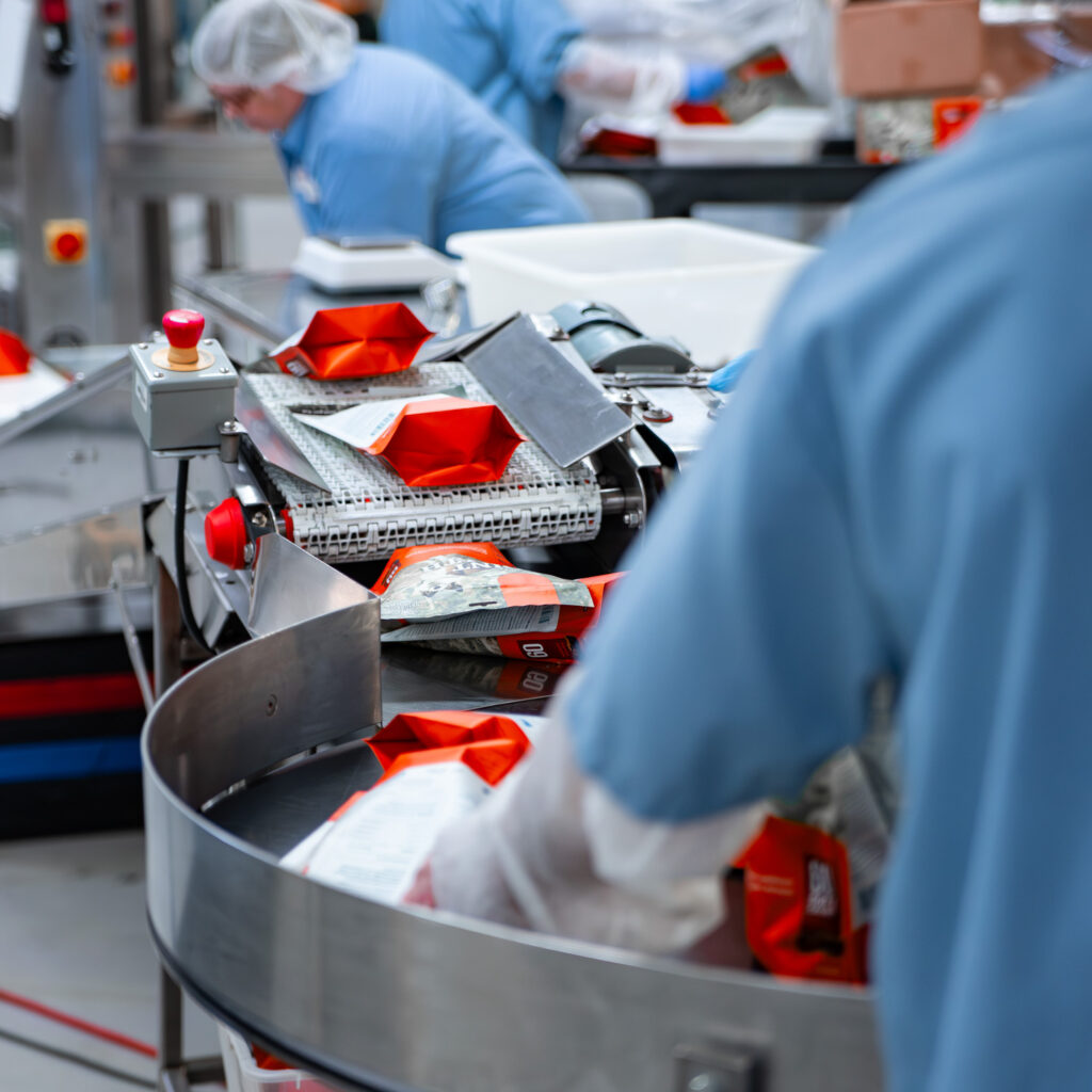 packing on conveyor with team member in foreground on the Vets Plus manufacturing floor