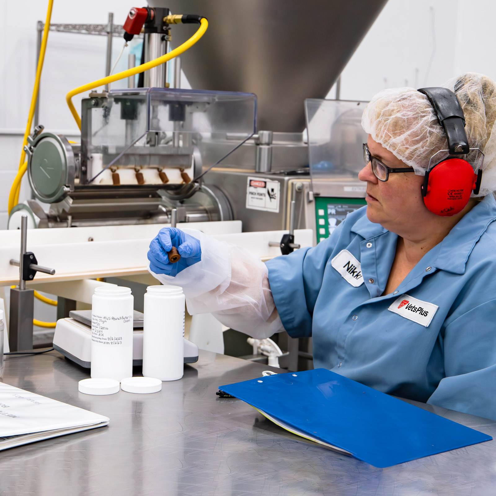 vets plus worker inspecting pill pocket next to manufacturing line